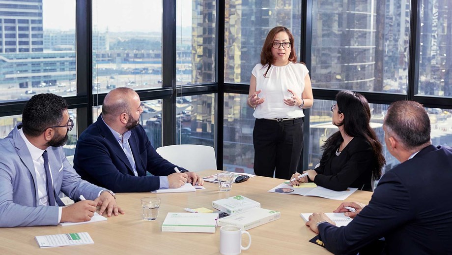 Flere medarbejdere lytter til en kvindelig leder til et kontormøde