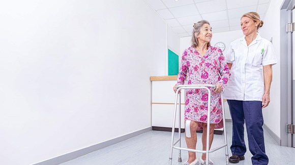 sygeplejerske, der står med patient i hospitalsomgivelser
