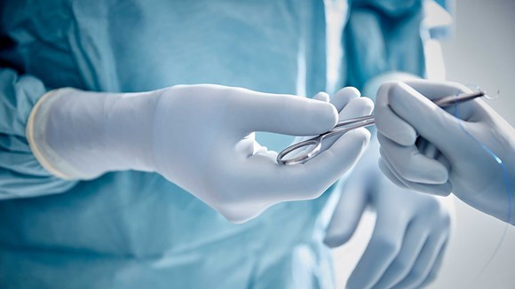Kirurger på operationsstuen tager handsker af